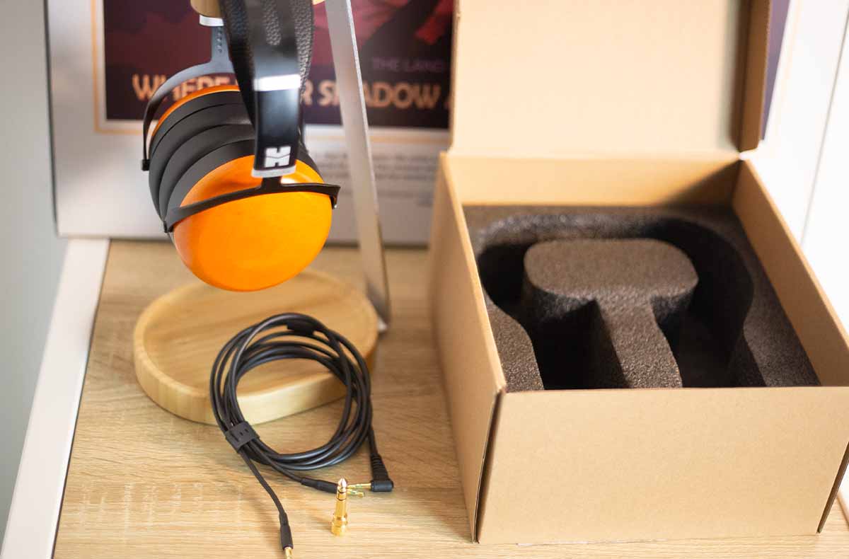 Le Sundara Closed-Back et ses coques orangées en bois de hêtre, ici posé sur son support : un casque au look affirmé, entre sobriété et chaleur visuelle.